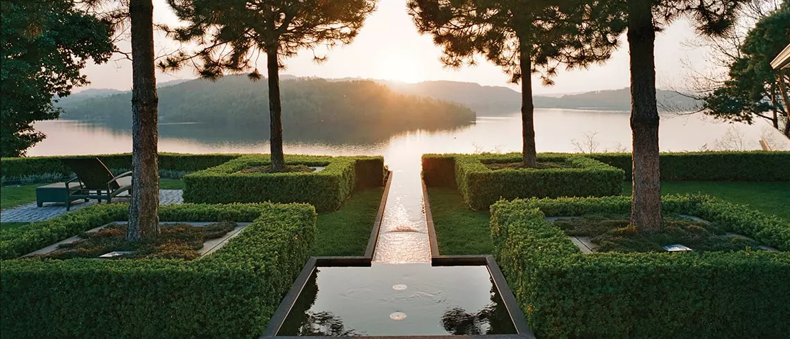 beautiful water feature that looks like it does out into a lake with islands in the background and the sun behind them